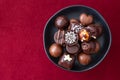 Assorted fancy milk and dark chocolate candy on a rustic black plate on a red background Royalty Free Stock Photo